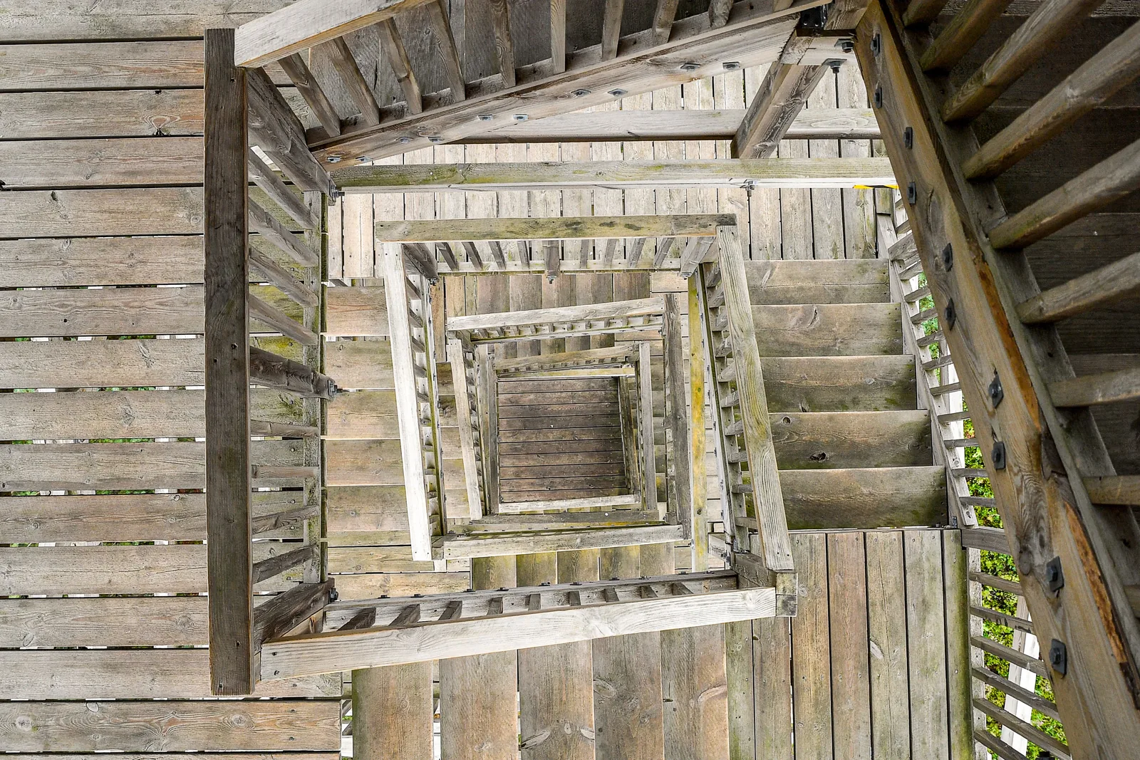 Looking down a square wooden staircase that spirals inward, flight after flight.