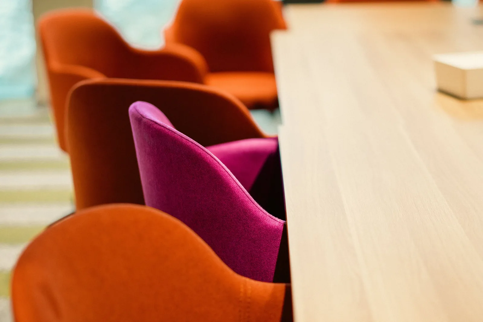 Close-up view of modern orange chairs around a conference table in an office setting.